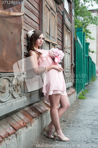 Image of beautiful woman with flower near old wooden house