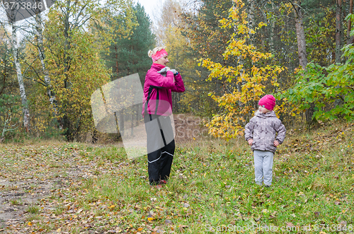 Image of Woman with girl doing aerobics in the autumn park