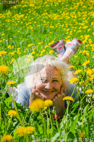 Image of A woman lies in a clearing and sniffs a flower  