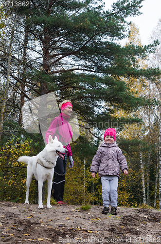 Image of Granny with her granddaughter and a dog walk in autumn Park  