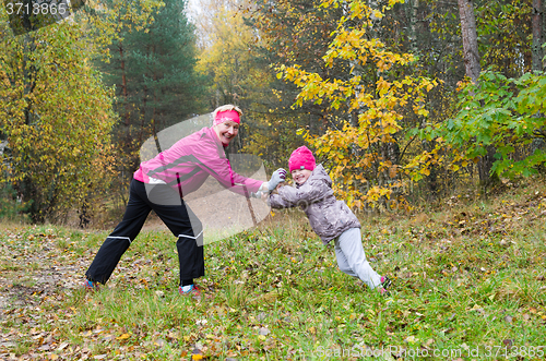 Image of Woman with girl doing aerobics in the autumn park