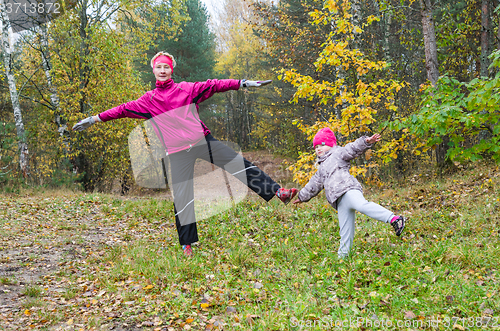 Image of Woman with girl doing aerobics in the autumn park