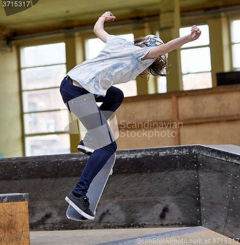 Image of Teen female skater jumping high indoors