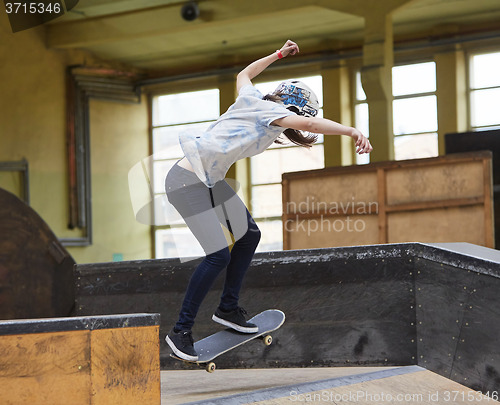 Image of Teen female skater jumping high indoors