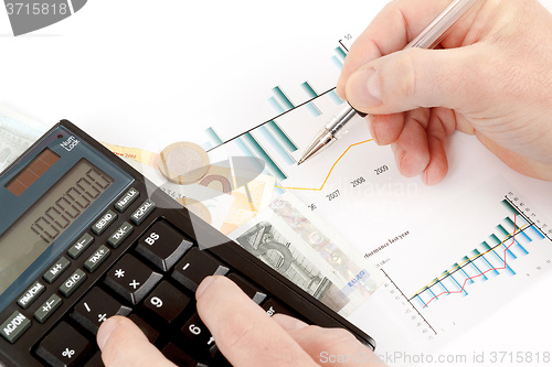 Image of calculator, charts, pen in hand, business cards, money, workplac