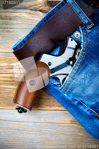 Image of silver revolver nagant with brown handle in the pocket