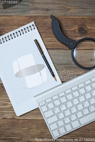 Image of notebook, pen, magnifying glass and computer keyboard