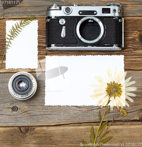 Image of mockup stillife with retro photo, camera, lens and pressed plant