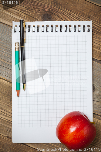 Image of scratchpad for taking notes, a pen, a pencil and an apple