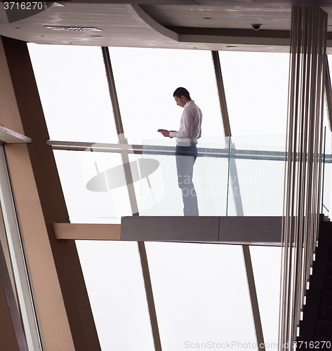 Image of young successful business man in penthouse apartment working on 