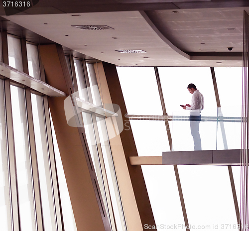 Image of young successful business man in penthouse apartment working on 