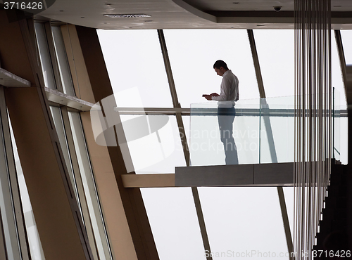 Image of young successful business man in penthouse apartment working on 