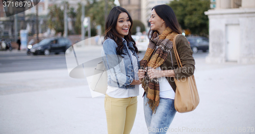 Image of Two stylish women chatting outdoors in a town