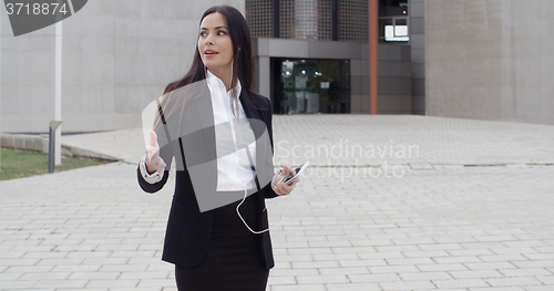 Image of Young woman taking a call using earplugs