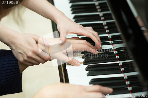 Image of Women\'s hands on the keyboard of piano. girl plays. music teacher