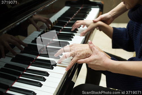 Image of Women\'s hands on the keyboard of piano. girl plays. music teacher