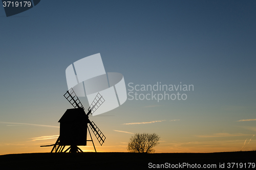 Image of Old windmill silhouette by sunset