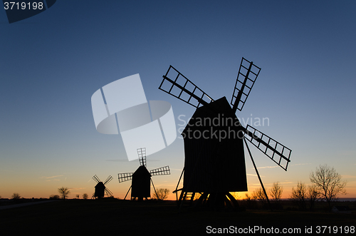 Image of Silhouettes of old windmills by sunset