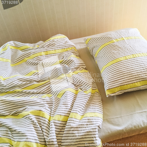 Image of Messy bed in morning sunlight