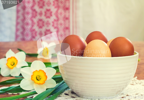 Image of Easter eggs in a ceramic vase and flowers daffodils.