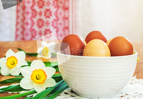 Image of Easter eggs in a ceramic vase and flowers daffodils.