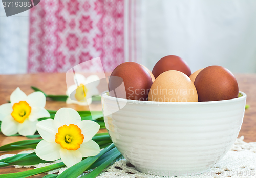 Image of Easter eggs in a ceramic vase and flowers daffodils.