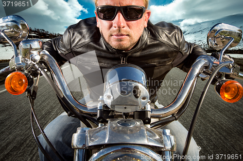 Image of Funny Biker in sunglasses and leather jacket racing on mountain 