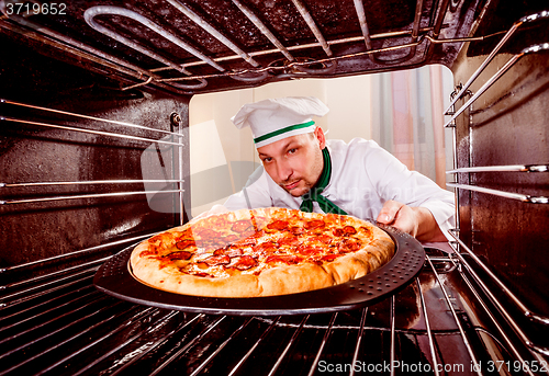 Image of Chef cooking pizza in the oven.