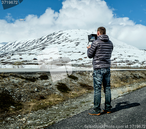 Image of Pilot controls the drone performing flight over the mountains