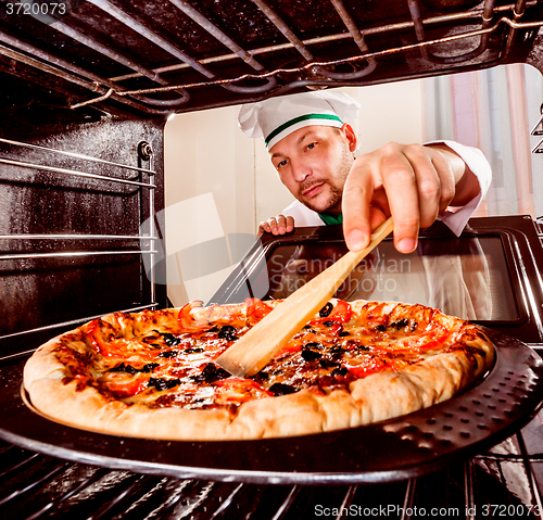 Image of Chef cooking pizza in the oven.