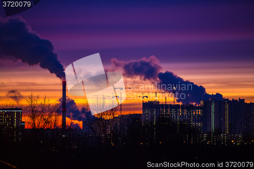 Image of Modern city in the evening at sunset. Smoke comes out of the pip