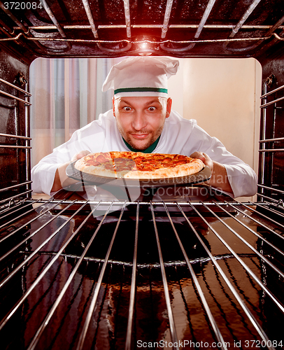 Image of Chef cooking pizza in the oven.