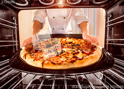 Image of Chef cooking pizza in the oven.