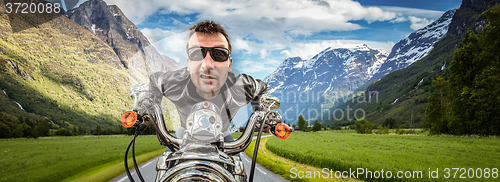 Image of Funny Biker in sunglasses and leather jacket racing on mountain 