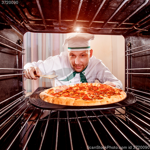 Image of Chef cooking pizza in the oven.