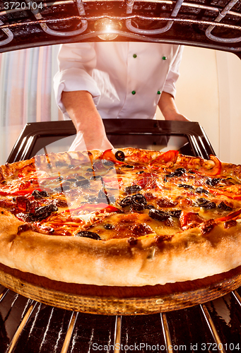 Image of Chef cooking pizza in the oven.