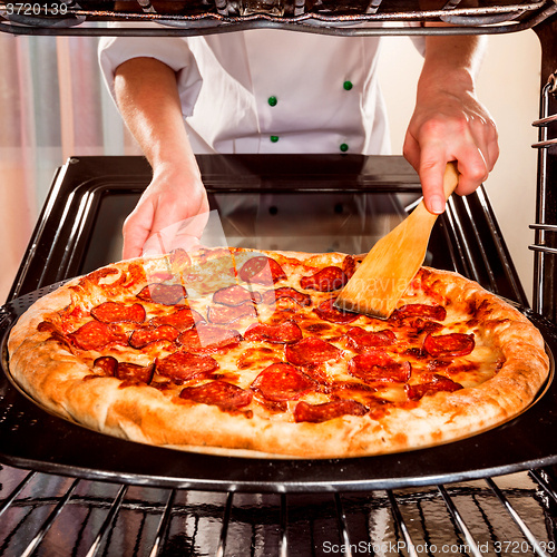 Image of Chef cooking pizza in the oven.