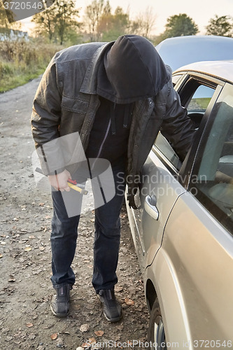 Image of Hooligan breaking into car