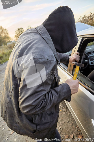 Image of Hooligan breaking into car