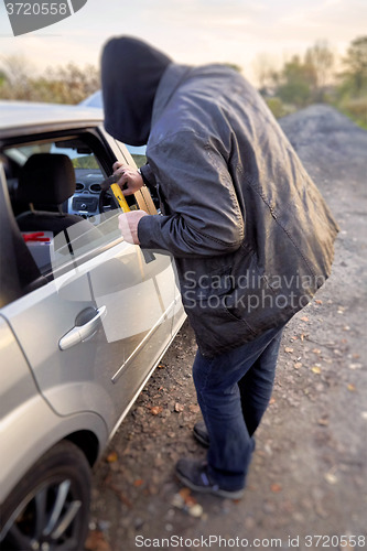 Image of Hooligan breaking into car