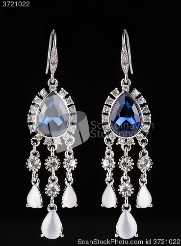 Image of earring with colorful blue gems on black background