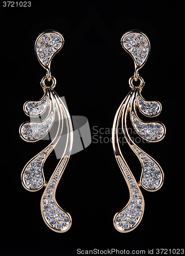Image of gold earrings with jewels on the black