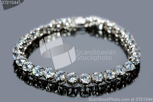 Image of golden bracelet with precious stones on grey background