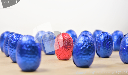 Image of one red easter egg in rows of blue eggs
