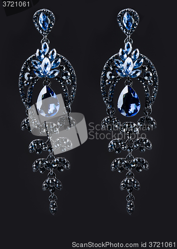 Image of earring with colorful blue gems on black background