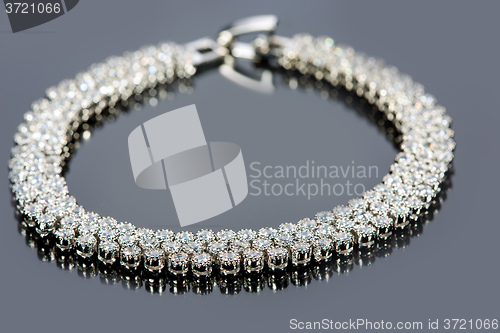 Image of golden bracelet with precious stones on grey background