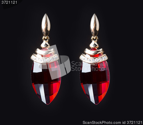 Image of earring with colorful red gems on black background