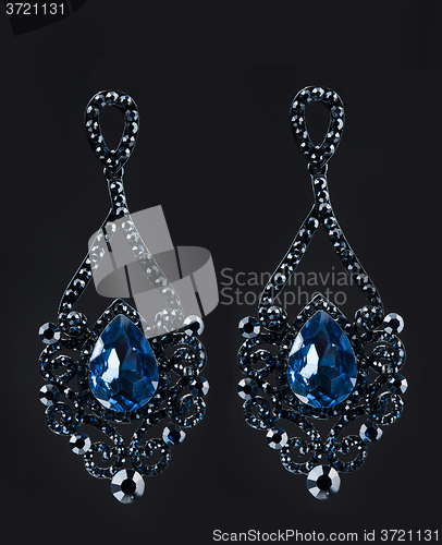 Image of earring with colorful blue gems on black background