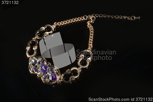 Image of golden bracelet with precious stones on black background