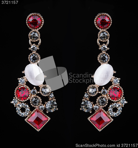 Image of earring with colorful red gems on black background